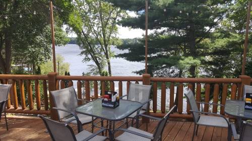 A wooden deck with tables and chairs overlooking a serene lake surrounded by trees.