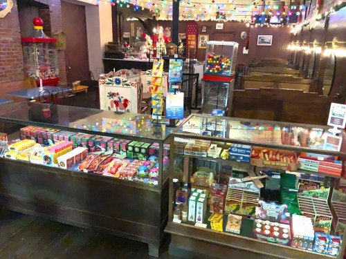 A vintage candy shop with colorful displays, festive lights, and wooden seating in a cozy atmosphere.