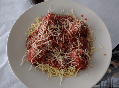 A plate of spaghetti topped with meatballs and marinara sauce, garnished with shredded cheese.