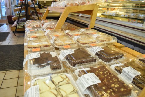 A display of assorted baked goods in clear containers on a wooden table in a bakery.