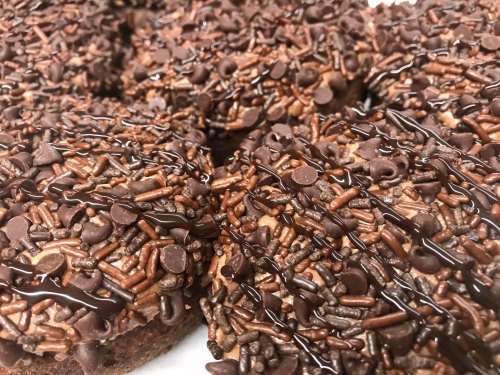 Close-up of chocolate-covered treats topped with chocolate sprinkles and drizzled with chocolate sauce.