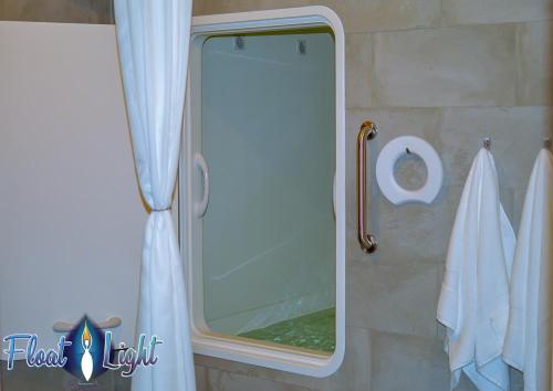 A clean, modern float tank room with a mirror, towels, and a soothing atmosphere.