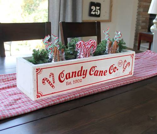 A festive centerpiece featuring a wooden box labeled "Candy Cane Co." filled with candy canes and greenery.