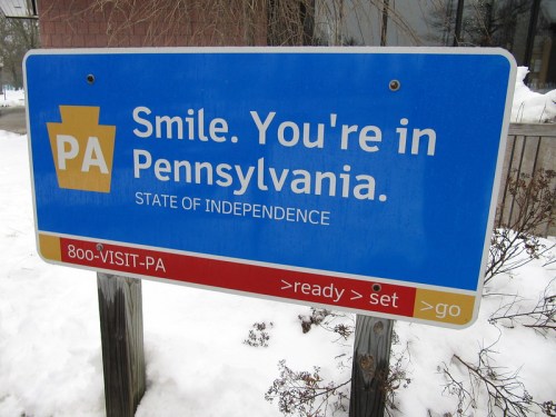 Blue sign welcoming visitors to Pennsylvania, stating "Smile. You're in Pennsylvania. State of Independence."