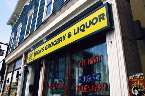 Sign for Don's Grocery & Liquor featuring "Late Night," "Burgers," and "Golden Fries" in bright neon colors.