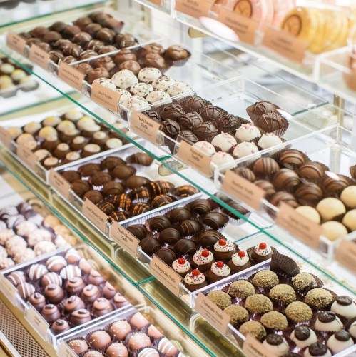 A display case filled with an assortment of beautifully crafted chocolates and truffles in various flavors and designs.