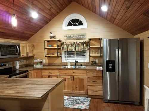 Cozy kitchen with wooden cabinets, stainless steel appliances, and a rustic ceiling, featuring a "Farm Fresh" sign.