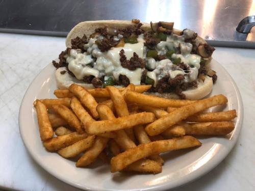 A loaded sandwich with ground beef, melted cheese, and peppers, served with a side of crispy French fries.