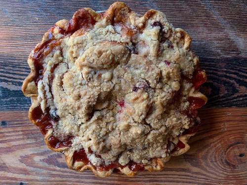 A freshly baked pie with a crumbly topping, resting on a wooden surface.