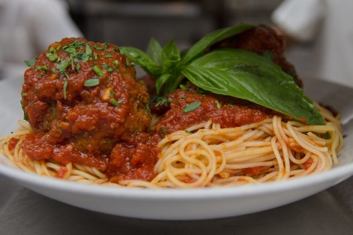 A plate of spaghetti topped with meatballs and fresh basil in a rich tomato sauce.