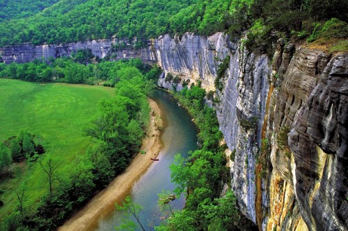 A scenic view of a river winding through lush green cliffs and trees, showcasing natural beauty and tranquility.
