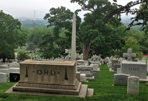 A cemetery with gravestones, featuring a prominent monument labeled "ORD" and the Washington Monument in the background.