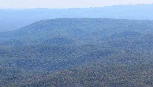 A panoramic view of rolling green mountains under a clear blue sky.