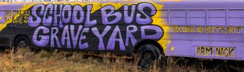 A colorful mural on a school bus reads "School Bus Graveyard" with playful phrases in purple and yellow.