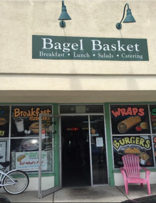 Exterior of Bagel Basket restaurant featuring a sign and colorful window displays for breakfast, lunch, and catering.