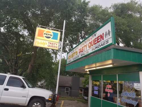 Sign for Christy's Tasty Queen featuring a Pepsi logo, with a truck parked outside and trees in the background.