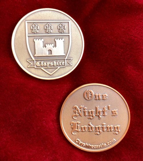 Two bronze coins on a red velvet background; one features a castle and the name "Clayshire," the other reads "One Night's Lodging."