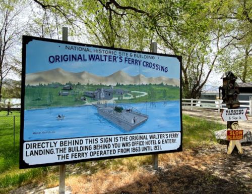 Sign for Walter's Ferry Crossing, detailing its history and location, with a scenic background of water and mountains.