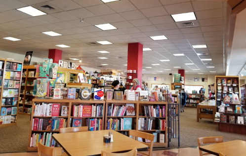 A cozy bookstore interior with wooden shelves filled with books, tables, and customers browsing.