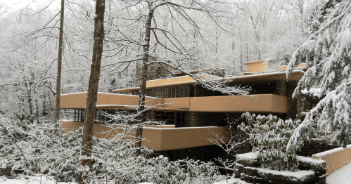 A modern house nestled in a snowy forest, surrounded by trees and greenery, showcasing a blend of architecture and nature.