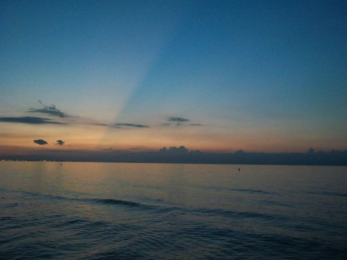 A serene ocean at dusk, with soft waves and a gradient sky transitioning from blue to orange.