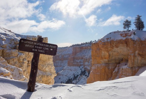 Signpost for Upper Inspiration Point, with snowy cliffs and a blue sky in the background at Bryce Canyon National Park.
