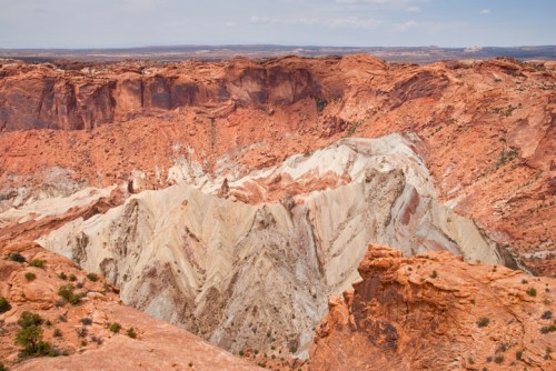 A vast canyon with layered red and white rock formations under a clear blue sky.
