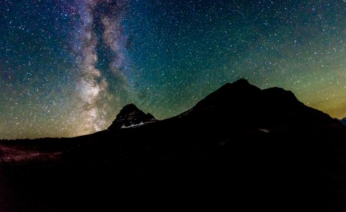 A starry night sky with the Milky Way arching over dark mountain silhouettes.