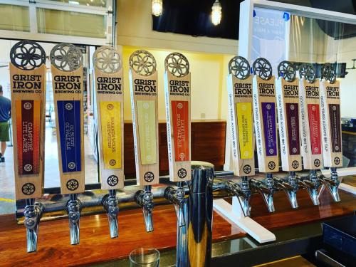A row of beer taps with various labels at Grist Iron Brewing Co, showcasing different craft beer options.