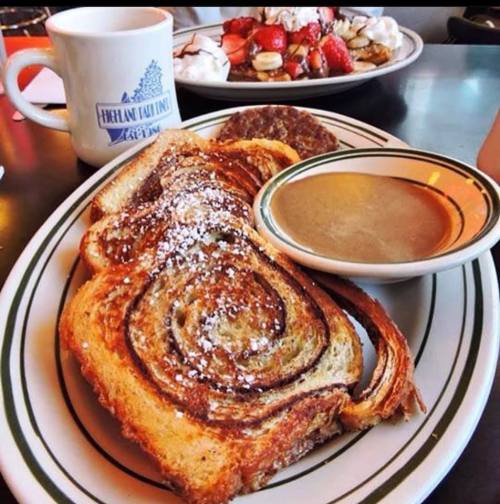 A plate of French toast dusted with powdered sugar, served with syrup, alongside a sausage patty and a cup of coffee.