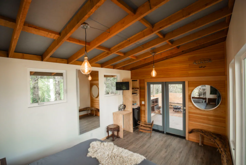 Cozy interior of a modern cabin with wooden beams, large windows, and a minimalist design.