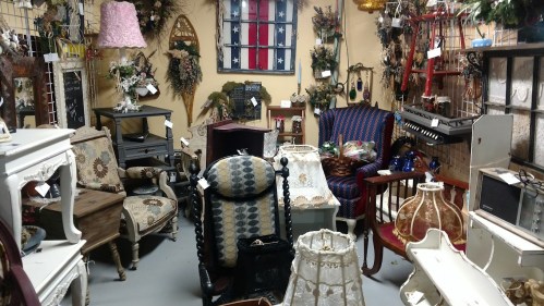 A cozy antique shop filled with various vintage furniture, decor, and accessories in a warm, inviting setting.