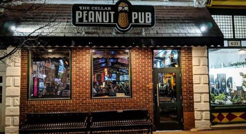 Exterior of The Cellar Peanut Pub, featuring a brick facade, large windows, and a sign with a peanut logo.