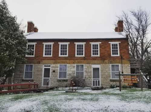 Historic brick house with a snowy yard, featuring a sign for Pearson House and a wooden ramp.