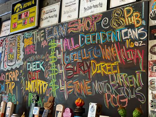 Chalkboard menu featuring colorful text with drink specials and pub information at The Cellar Peanut Pub.