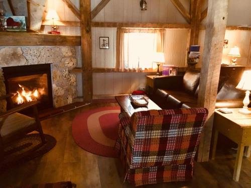 Cozy cabin interior with a fireplace, plaid armchair, sofa, and warm lighting, creating a welcoming atmosphere.