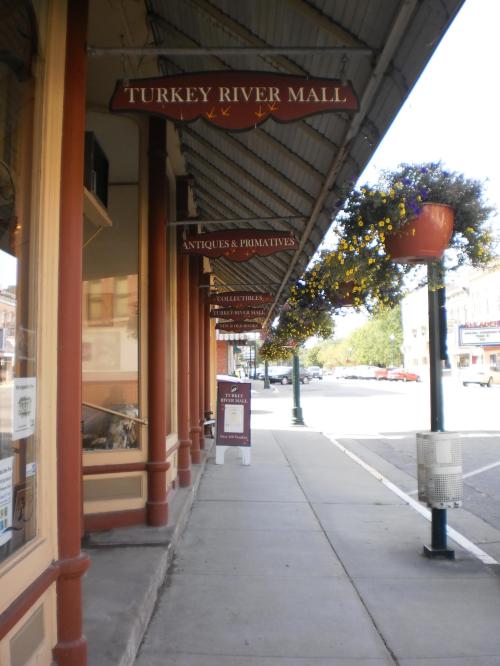 A quaint street view featuring the Turkey River Mall sign and hanging flower baskets along a sidewalk.