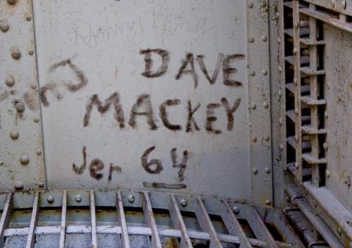 Graffiti on a metal surface featuring the names "Dave Mackey" and "Danny King," with "Jer 64" inscribed below.