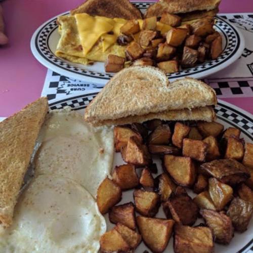 Two plates of breakfast: one with toast and cheese, the other with eggs and crispy potato cubes.
