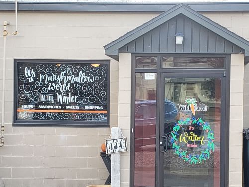 A storefront with a colorful sign reading "It's a Marshmallow World in the Winter" and a welcoming door display.