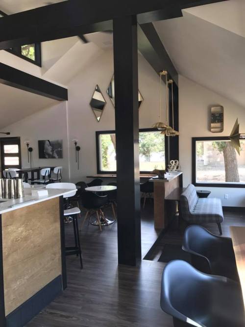 Modern interior of a stylish café featuring high ceilings, wooden accents, and a mix of seating arrangements.