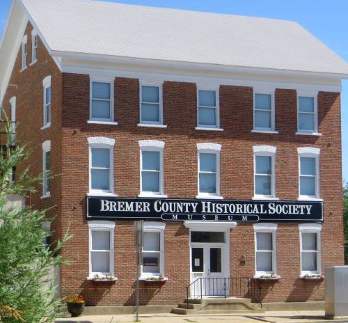 Brick building with a sign reading "Bremer County Historical Society Museum" and flower boxes under the windows.