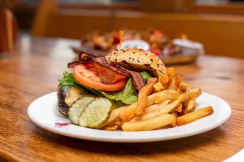 A juicy burger with lettuce, tomato, bacon, and pickles, served with crispy fries on a wooden table.