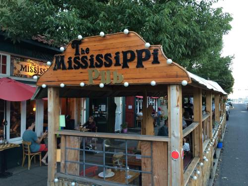 Exterior view of The Mississippi Pub, featuring wooden signage and outdoor seating along a street lined with trees.