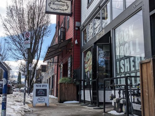 A street view of a colorful building with a sign for "Mississippi" and a patio open sign outside, snow on the ground.