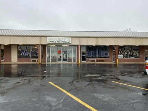 Exterior of Goody's Family Restaurant in Plainfield, with a sign reading "We're in this together." Wet pavement visible.