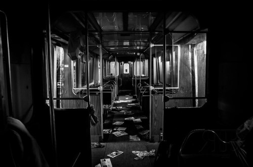 A dimly lit, abandoned train interior with scattered papers and debris on the floor.