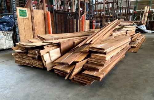 A large stack of wooden planks and boards arranged neatly in a warehouse.