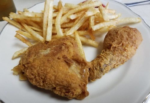 A plate with two pieces of fried chicken and a serving of golden French fries.