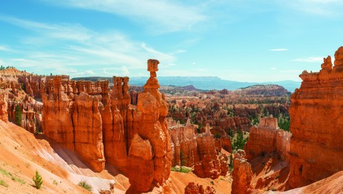 A panoramic view of Bryce Canyon, featuring unique rock formations and vibrant orange hues under a clear blue sky.